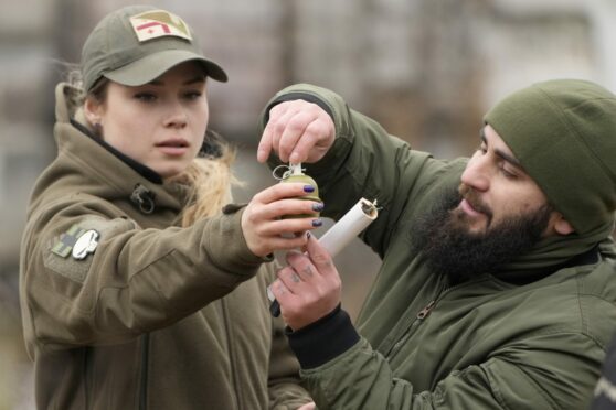 An instructor in Kyiv shows a young woman how to use a grenade during training with members of Georgian Legio, a 200-strong group of Georgian paramilitaries formed to fight Russian troops in 2014 and now helping train Ukrainian civilians in combat