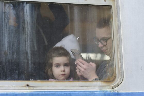 A girl watches from from a train carriage waiting to leave Ukraine for neighboring countries at the railway station in Lviv,western Ukraine