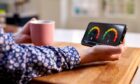 Close Up Of Woman Holding Smart Energy Meter In Kitchen