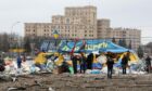 People stay by the All for Victory Tent of volunteers after a missile launched by Russian invaders hit outside the Kharkiv Regional State Administration building in Svobody (Freedom) Square.