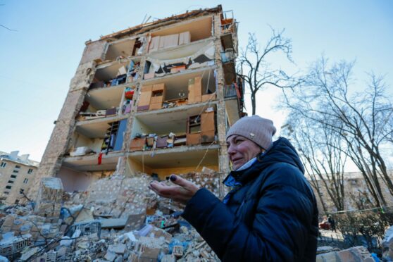 A woman surveys the remains of a block of flats in Kyiv, one of many non-military targets attacked by Russian  forces, on Friday