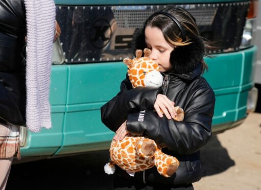 A young refugee hugs her toy giraffe at a border crossing in Palanca, Moldova, after fleeing from Ukraine.