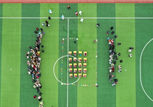 An aerial view shows primary pupils at their desks on the playing field in Tengzhou City during a Covid drill.
