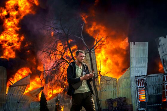 A man smokes a cigarette as he walks away from a burning building after a Russian strike on Kharkiv.