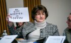 Forced adoption campaigner Marion McMillan, who as a 17-year-old was made to give up her son, holds a handwritten sign to express her anguish to MSPs at Holyrood on Thursday
