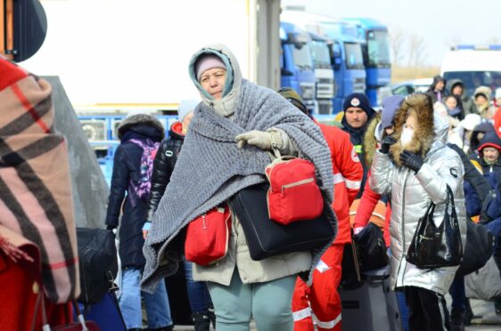 Exhausted and huddled in blankets to stay warm, Ukrainian women arrive in Isaccea, Romania. They carry the few belongings they packed into bags before fleeing the rockets and bombs in their Ukrainian homeland