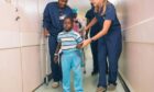 Mercy Ships staff help Diacko, a patient who travelled 300 miles to have surgery on Africa Mercy in Senegal.