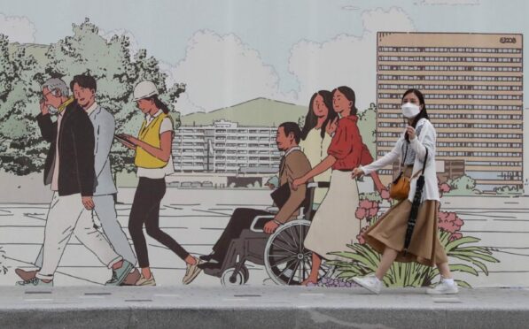 A masked woman walks beside a mural in Seoul, South Korea, where Devi Sridhar says learning from past mistakes helped to secure one of the world’s lowest pandemic death tolls.