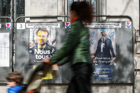 A woman walks past billboards for French presidential candidates Macron and Le Pen in Paris as voters decide on the country’s future