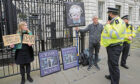 Police officer talks to protesters in front of the entrance to Downing Street in London.