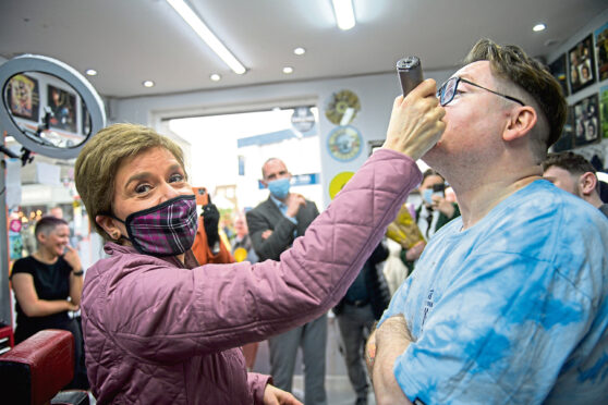 Nicola Sturgeon shaves barber Tony Cairney's beard at the Iconic Gents Hair in East Kilbride.