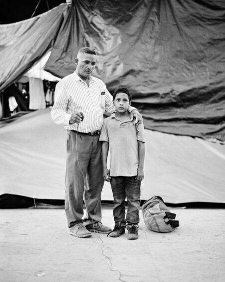 Migrantes: Edwardo Benavides, age 40 and his son Jonathon Benavides Reyes, age 9, are migrants from La Union, El Salvador. They took a portrait at an informal migrant camp at a municipal park in Reynosa, Tamaulipas, Mexico on 5 May 2021.