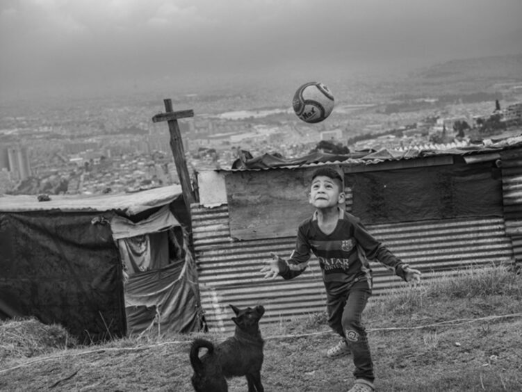 The Children of the Financial Collapse in Venezuela: A young boy playing football on the hills in Soacha, outside Bogotá in Colombia. Most migrants live in the neighbourhood illegally, and are often forced away by police.