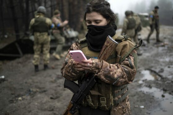 Ukrainian soldier known only as Dasha checks her phone during a search for Russian troops after their withdrawal from villages on the outskirts of Kyiv