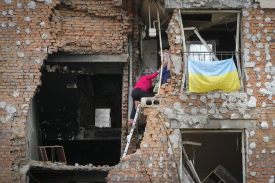 Ukrainian residents climb into the ruins of their home after it was hit by Russian shelling in Irpin, close to Kyiv, yesterday
