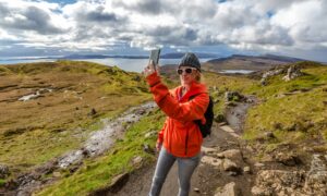 A visitor takes a selfie while trekking to The Old Man of Storr on the Isle of Skye, one of Scotland’s most popular destinations