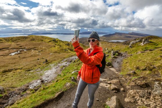 A visitor takes a selfie while trekking to The Old Man of Storr on the Isle of Skye, one of Scotland’s most popular destinations