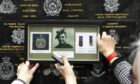 Relatives of Private James McPhilemy hold up his photo and medals at the plaque at Glasgow Central Station