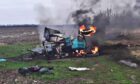The remains of a tractor blown up by a Russian landmine burns in a field in Chernihiv, Ukraine