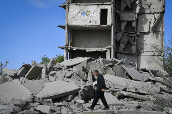 A local resident walks next to a house destroyed in a Russian shelling in Kramatorsk, Ukraine,