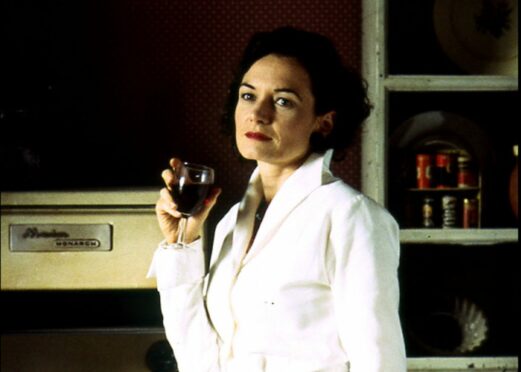 Cookery writer Elizabeth David poses in the kitchen with a glass of wine