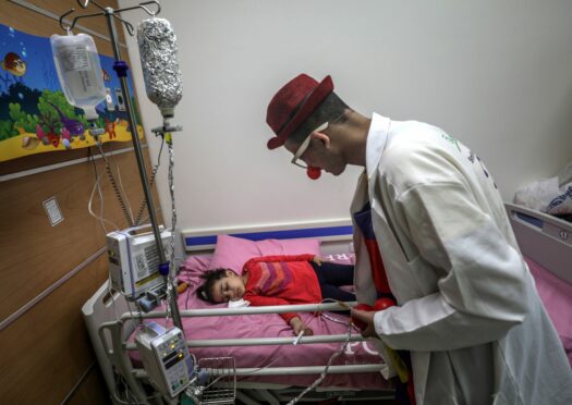 Jihad Bearkat, a cancer patient, clowns around with a young girl on the children’s cancer ward at al-Rantisi hospital in Gaza