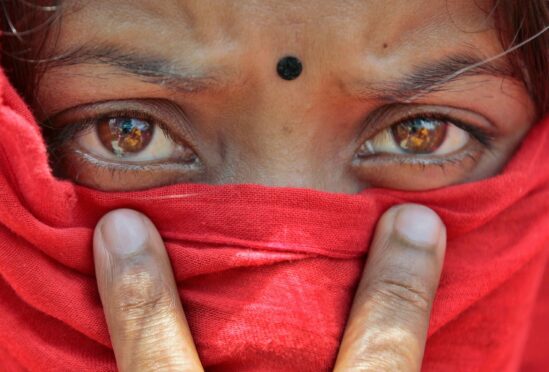 A worker of the closed Swan Garments factory covers her face with a scarf to shelter from the sun as she protests outside the Bangladesh Garment Manufacturers and Export Association office in Dhaka, Bangladesh
