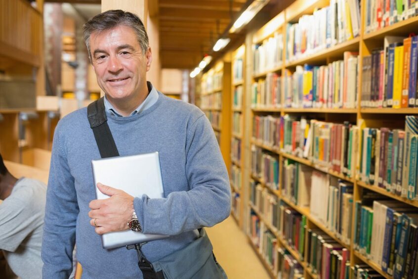 man holding a book in a university library