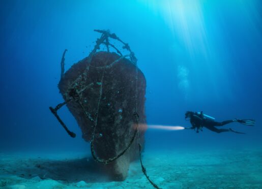 A scuba diver inspects a sunken shipwreck off the Maldives