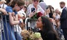 The Duchess of Sussex speaks to a young well-wisher outside Windsor Castle last night as she joins her husband Harry and the Prince and Princess of Wales to thank the crowds for their support