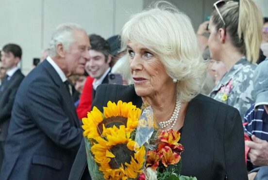 The Queen Consort is given a bouquet of sunflowers as she leaves the Scottish Parliament with King Charles on Monday