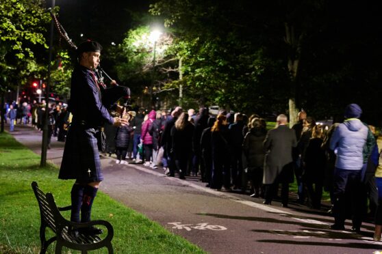 A lone piper serenades the queue in the Meadows as thousands turn out to see Queen lying at rest