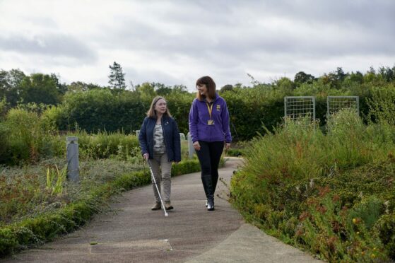 Sight Scotland veteran worker walking in the outdoors with visually impaired girl