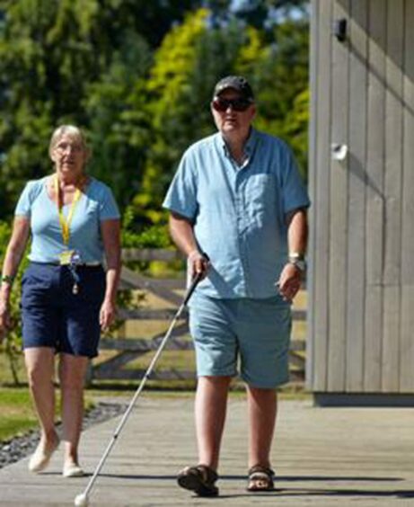 couple walking, man losing sight walks with long cane