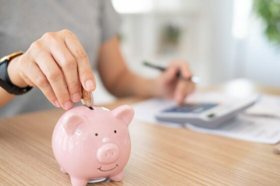 Person putting coin in piggy bank. Article about bank or credit union