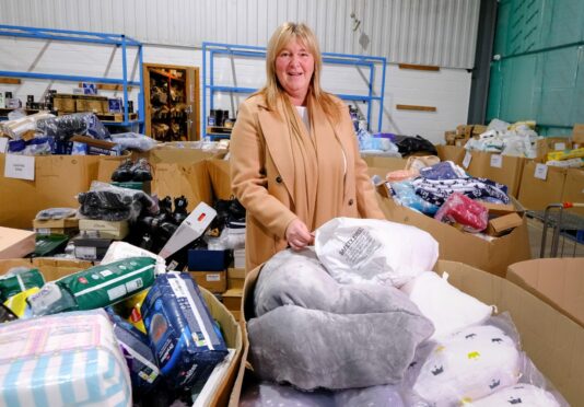 Pauline Buchan, strategic manager of The Cottage Family Centre charity, sifts through items at Amazon’s Lochgelly 
depot in Fife