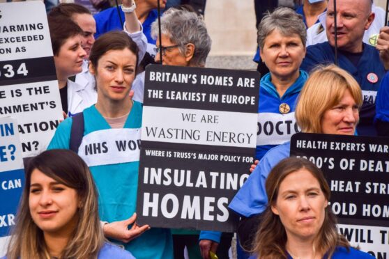 A protester holds a placard stating that British homes are the leakiest in Europe and calling for insulation.