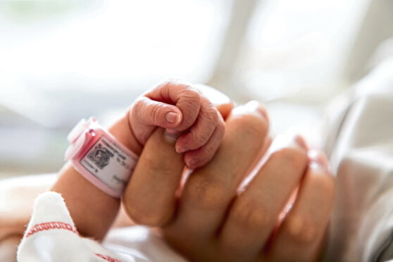 A tiny baby grasps a finger on a neonatal unit but staffing levels are risking care.