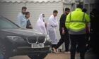 People thought to be migrants pass the car of Home Secretary Suella Braverman  (left) during her visit to the Manston immigration short-term holding facility.