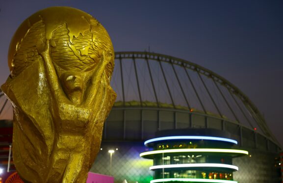 A giant replica World Cup trophy at the Khalifa International Stadium at sunset