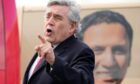 Former PM Gordon Brown talks at a rally in front of a bus with an image of Scottish Labour Leader Anas Sarwar in Glasgow in May
