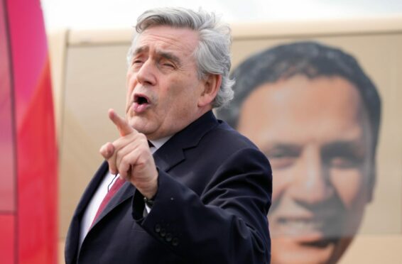 Former PM Gordon Brown talks at a rally in front of a bus with an image of Scottish Labour Leader Anas Sarwar in Glasgow in May