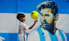 A fan in front of a mural of Lionel Messi, in Bangladesh