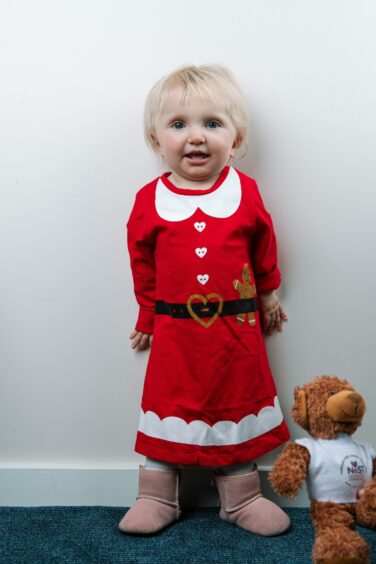 Smiling little Isabella, dressed in a Christmas outfit, shows she can now stand with a little support
