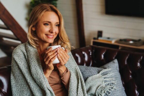 Woman wrapped in blanket drinking hot tea.
