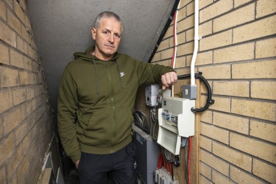 John Crossan in communal electrical supply room at his home in Glasgow