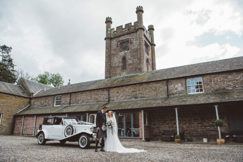 couple poses with a bridal car in Abercairny Estate, one of the top Scottish wedding suppliers