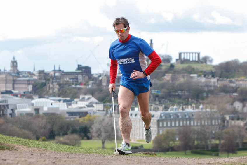 A photo of Steven Waterston running with a white cane in Edinburgh