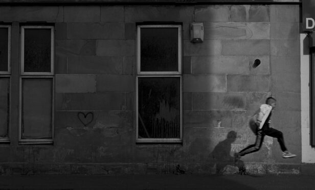 A boy runs down a street in Govanhill in Glasgow as experts call for urgent action to close the poverty gap.