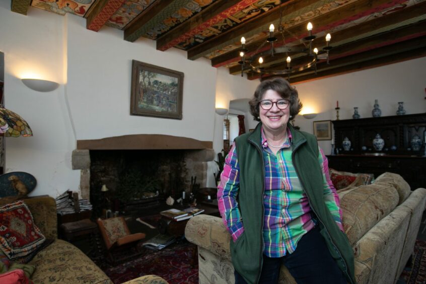 Janet Brennan-Inglis in "The Great Hall" - their living room, with the timber ceiling painted with intricate designs